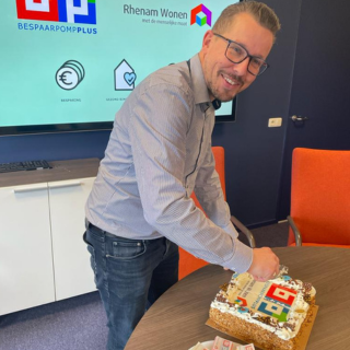 Gerdo ter Burg, projectleider bij Rhenam Wonen snijdt taart bij Rhenam Wonen evenement